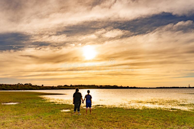 Muchacho y muchacha que miran puesta del sol fotografía de archivo Muchacho y muchacha que miran puesta del sol fotografía de archivo