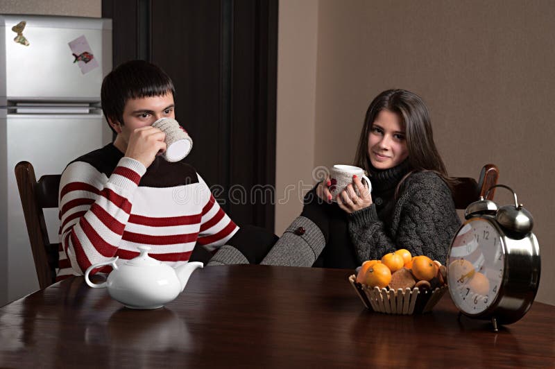 Muchacho y muchacha que se sientan en una tabla y un té de consumición imagenes de archivo Muchacho y muchacha que se sientan en una tabla y un té de consumición imagenes de archivo