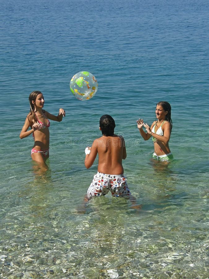 Muchacho y muchachas que juegan con la bola en el mar imagen de archivo Muchacho y muchachas que juegan con la bola en el mar imagen de archivo
