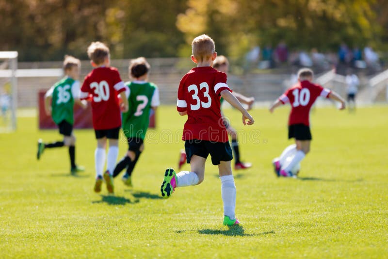 Muchachos que golpean fútbol con el pie en el campo de deportes Una imagen del deporte de la acción de un grupo de niños que jueg