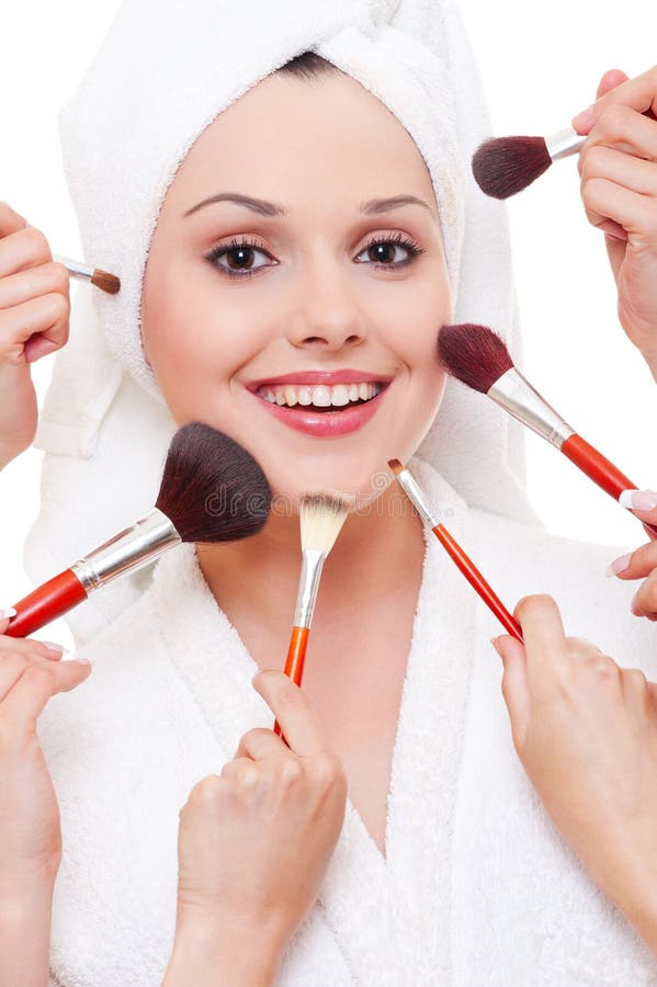 Many hands applying make-up to beautiful smiley woman. Many hands applying make-up to beautiful smiley woman