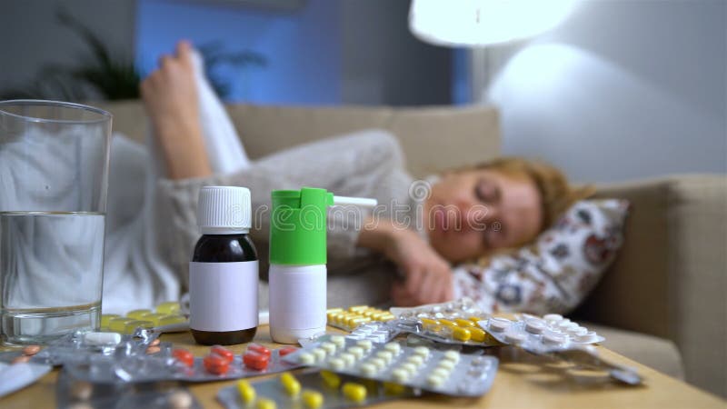 Muchas píldoras y medicinas en una tabla en Front Of una mujer joven enferma en el sofá almacen de metraje de vídeo