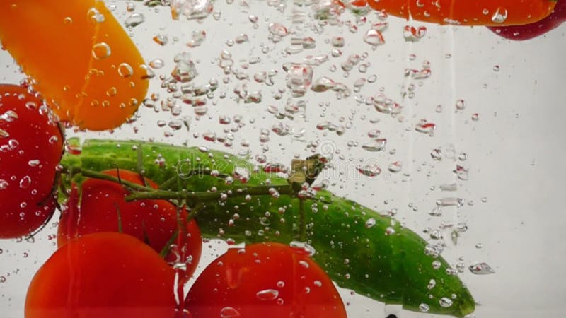 Muchas verduras frescas y brillantes caen bajo el agua con salpicaduras y burbujas almacen de metraje de vídeo