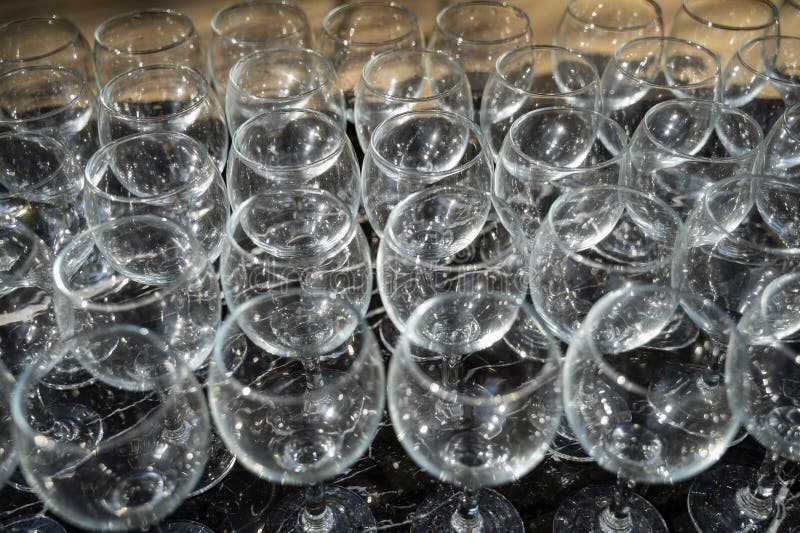 Muchos vasos de vino limpios y vacíos en un fondo oscuro a la luz del día foto de archivo