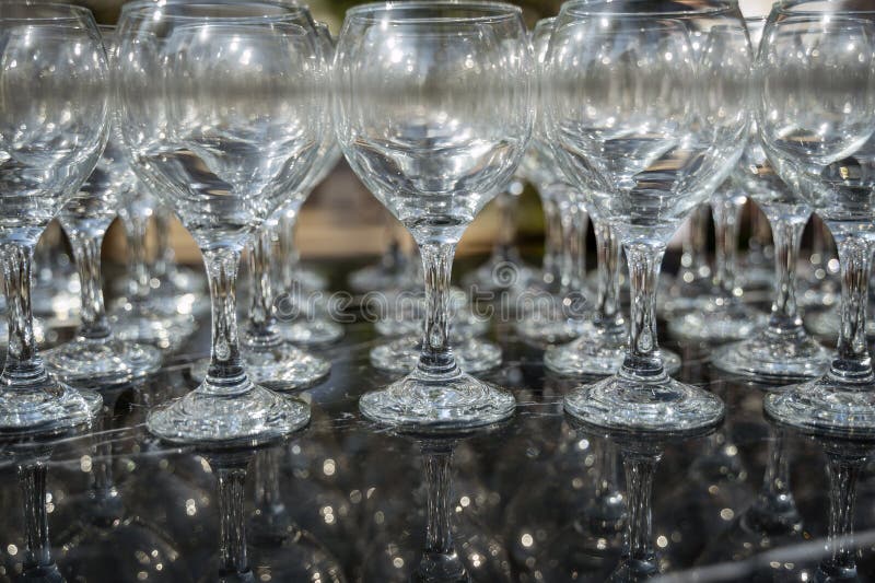 Muchos vasos de vino limpios y vacíos en un fondo oscuro a la luz del día fotografía de archivo