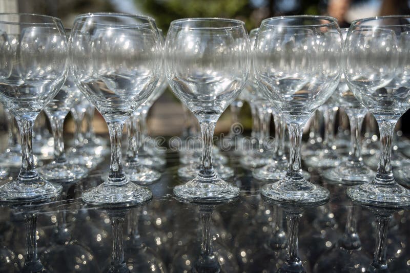 Muchos vasos de vino limpios y vacíos en un fondo oscuro a la luz del día imagen de archivo libre de regalías