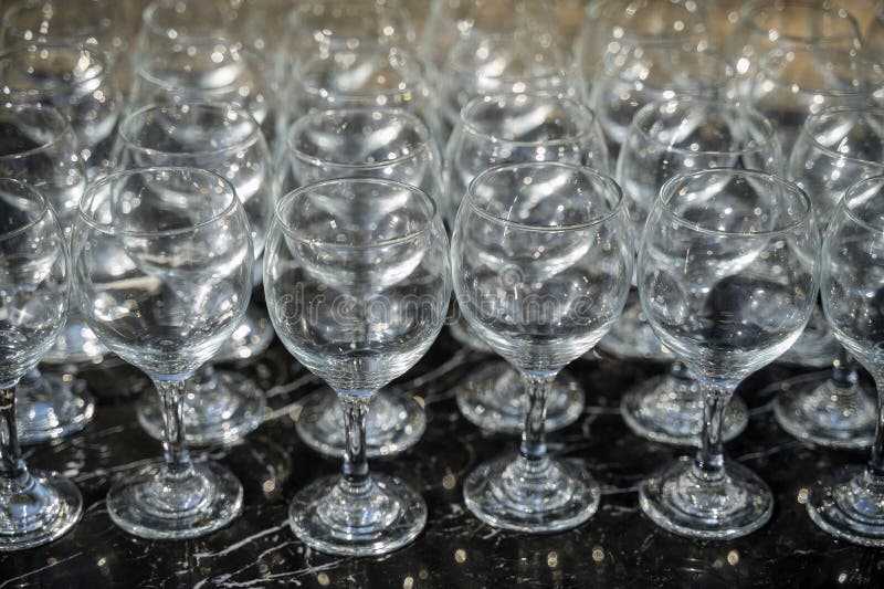 Muchos vasos de vino limpios y vacíos en un fondo oscuro a la luz del día imágenes de archivo libres de regalías