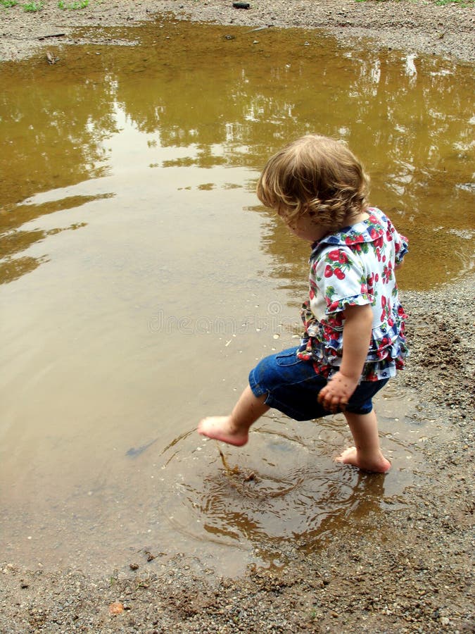 Little girl playing in a mud puddle. Little girl playing in a mud puddle