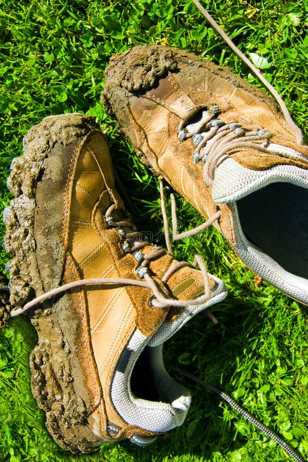 A pair of very muddy walking shoes drying in the sun