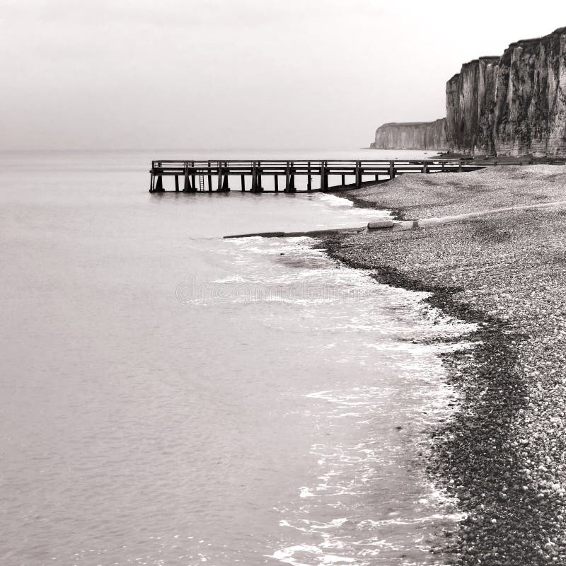 Muelle en el mar y acantilados de Rocky en la playa de la roca de la playa fotografía de archivo Muelle en el mar y acantilados de Rocky en la playa de la roca de la playa fotografía de archivo