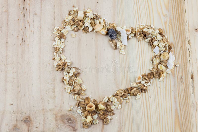 Muesli en forme de coeur et céréale sur la table en bois photographie stock libre de droits Muesli en forme de coeur et céréale sur la table en bois photographie stock libre de droits