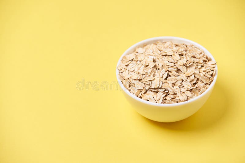 Muesli pour la nourriture saine de petit déjeuner Fond jaune Cuvette blanche photos stock Muesli pour la nourriture saine de petit déjeuner Fond jaune Cuvette blanche photos stock