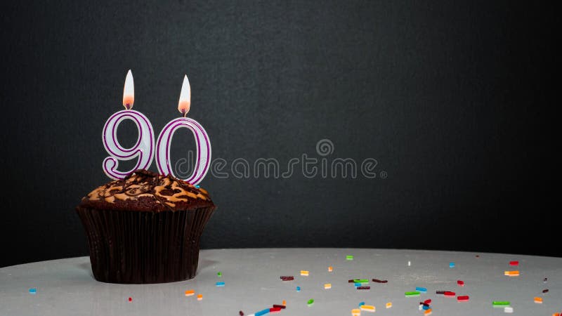 Muffin on black with a number from a candle number 90. Copy space, a pie on a black background, a card for congratulations on your birthday, anniversary. Muffin on black with a number from a candle number 90. Copy space, a pie on a black background, a card for congratulations on your birthday, anniversary