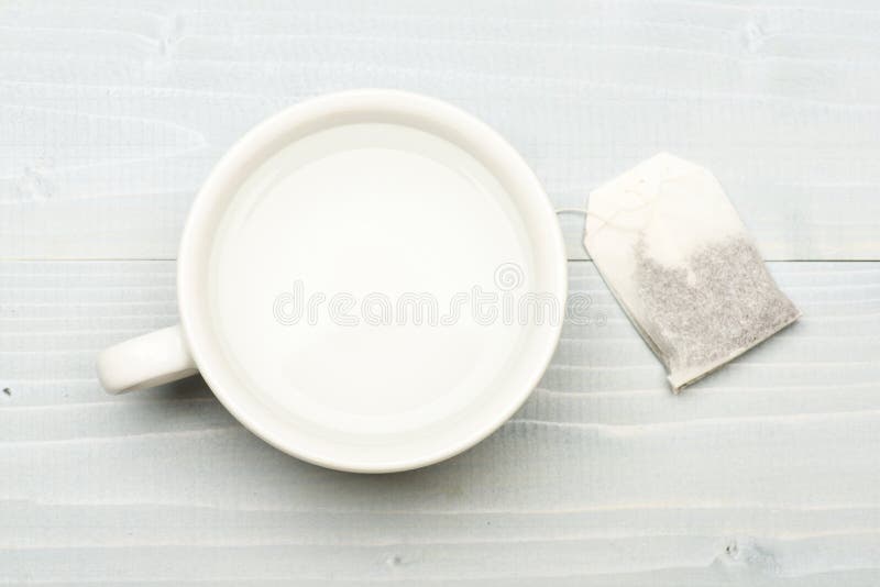 Mug filled with boiling water and teabag on white background. Process of tea brewing in ceramic mug, top view. Cup or