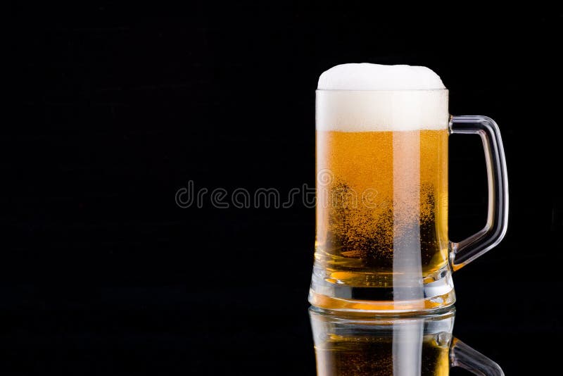 Mug fresh beer with cap of foam on a black