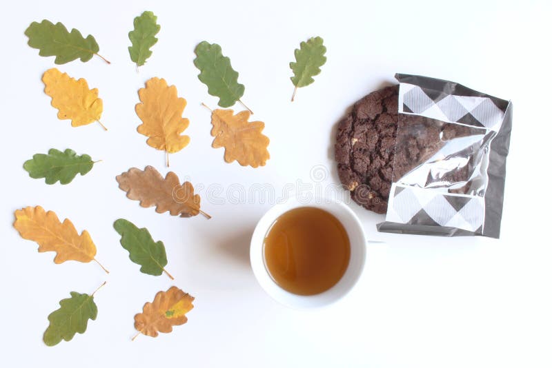 Mug with warm tea and cookies,fallen autumn leaves on white wooden table .Top view. Autumn, cozy composition. Mug with warm tea and cookies,fallen autumn leaves stock photo Mug with warm tea and cookies,fallen autumn leaves on white wooden table .Top view. Autumn, cozy composition. Mug with warm tea and cookies,fallen autumn leaves stock photo
