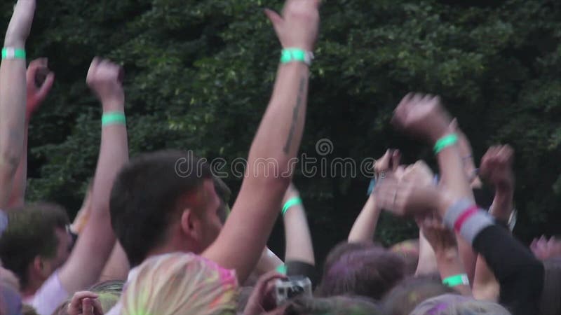 Muitas mãos que acenam acima no ar, salto feliz dos jovens, partying no festival