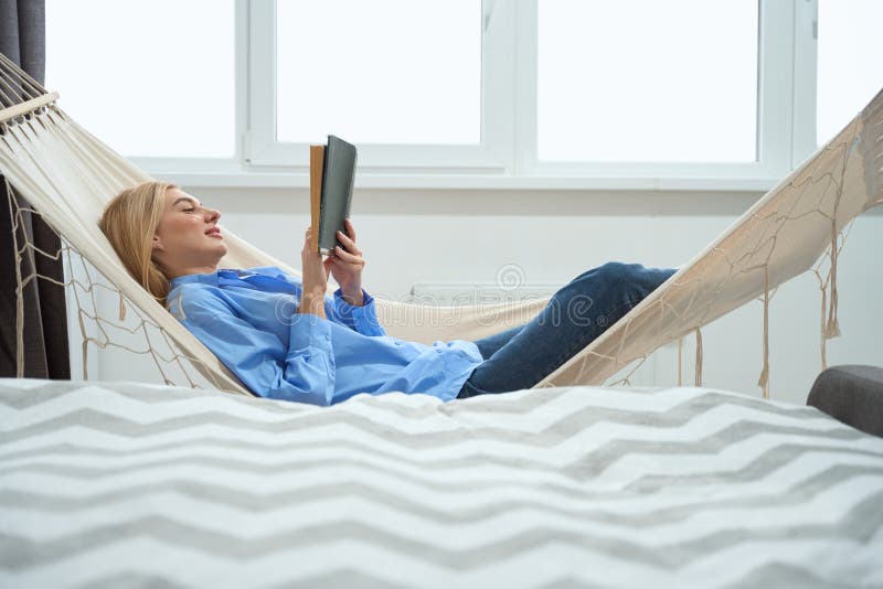 Mujer absorta en la novela de lectura por la mañana imagenes de archivo
