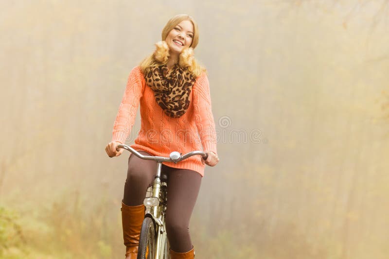 Mujer activa feliz montando bicicleta en el parque de otoño fotografía de archivo