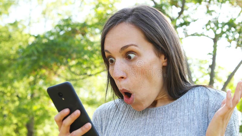 Mujer adulta sorprendida que comprueba el teléfono