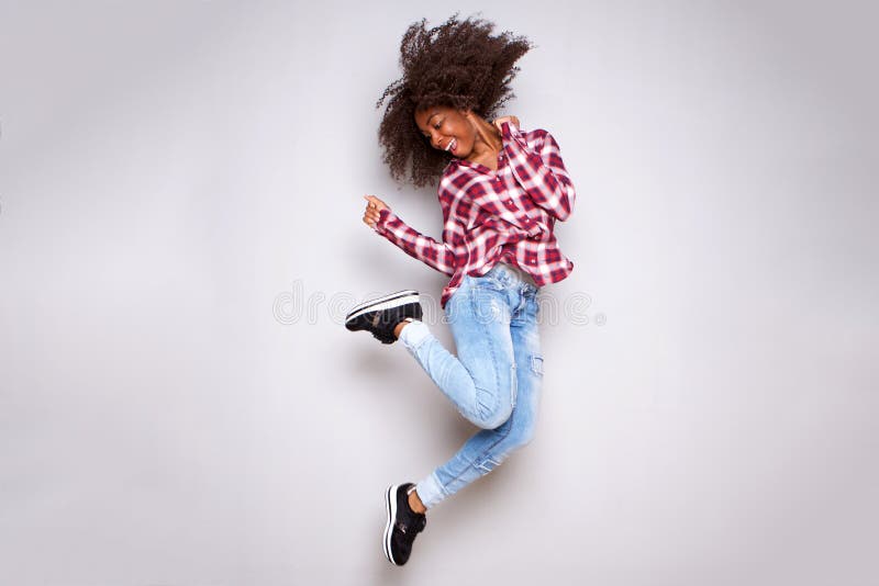 Mujer africana joven alegre del cuerpo completo que salta en aire sobre el fondo blanco fotografía de archivo Mujer africana joven alegre del cuerpo completo que salta en aire sobre el fondo blanco fotografía de archivo
