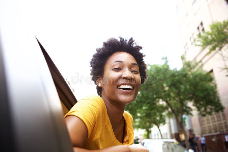 Mujer africana joven sonriente que mira hacia fuera la ventanilla del coche foto de archivo libre de regalías Mujer africana joven sonriente que mira hacia fuera la ventanilla del coche foto de archivo libre de regalías