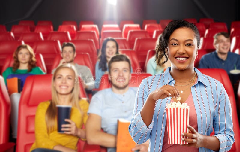 Mujer africana que come las palomitas en el cine fotos de archivo Mujer africana que come las palomitas en el cine fotos de archivo