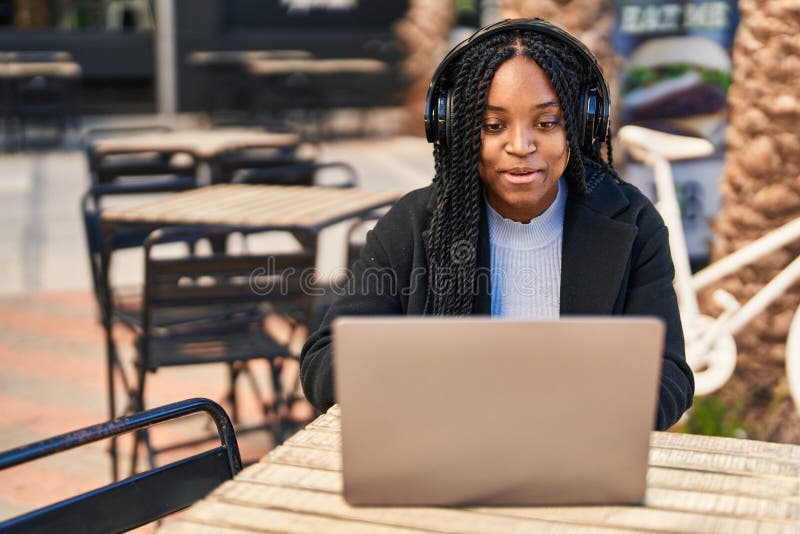 Mujer afroamericana con videollamada sentada en la mesa en la terraza de la cafetería fotografía de archivo libre de regalías