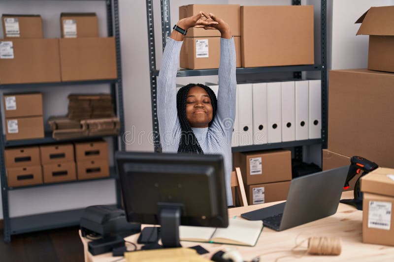 Mujer afroamericana ecommerce trabajadora de negocios usando un portátil estirando los brazos en la calle foto de archivo