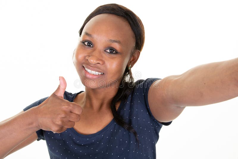 Mujer afroamericana joven alegre que usa la presentación sonriente del selfie del teléfono móvil en el fondo blanco foto de archivo libre de regalías Mujer afroamericana joven alegre que usa la presentación sonriente del selfie del teléfono móvil en el fondo blanco foto de archivo libre de regalías