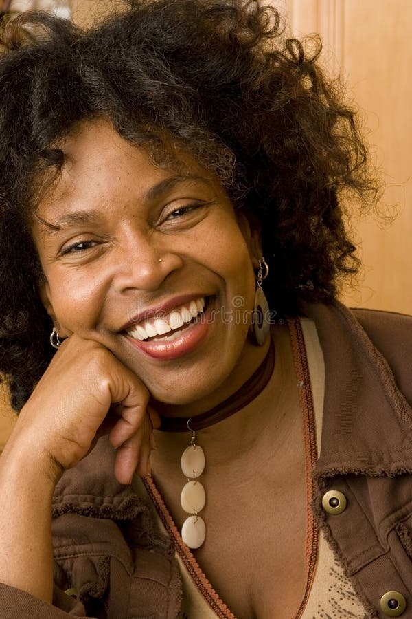 Mujer afroamericana madura feliz que sonríe en casa fotografía de archivo Mujer afroamericana madura feliz que sonríe en casa fotografía de archivo