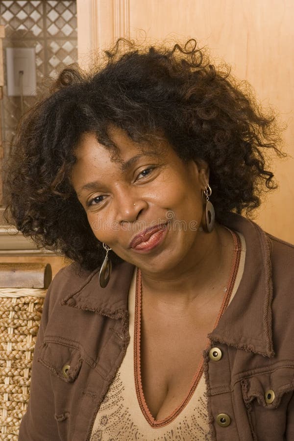 Mujer afroamericana madura feliz que sonríe en casa fotos de archivo Mujer afroamericana madura feliz que sonríe en casa fotos de archivo