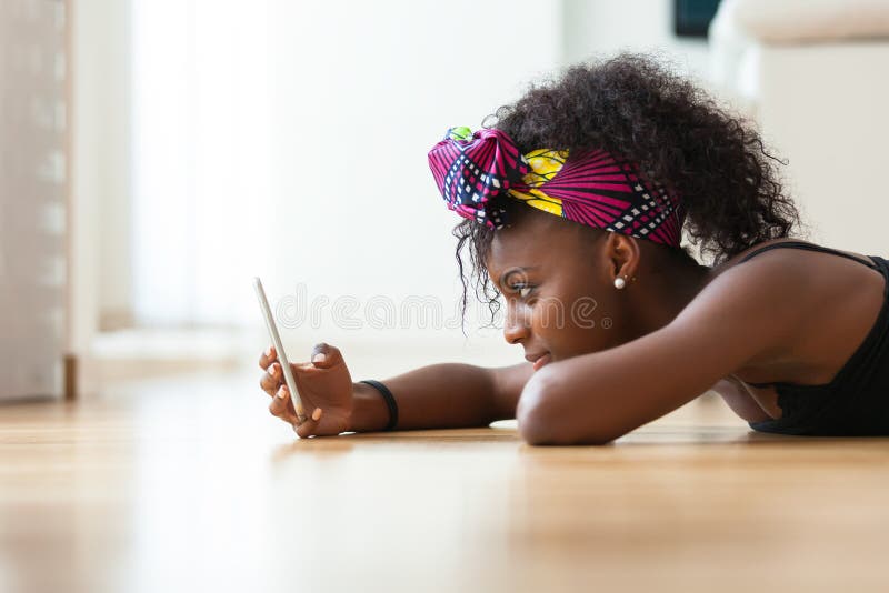 Mujer afroamericana que envía un mensaje de texto en un teléfono móvil imágenes de archivo libres de regalías Mujer afroamericana que envía un mensaje de texto en un teléfono móvil imágenes de archivo libres de regalías