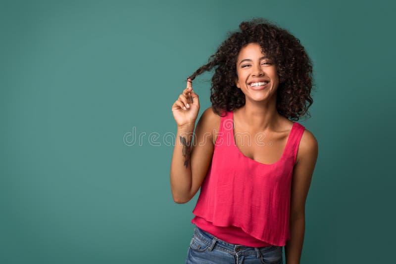 Mujer afroamericana que toca su pelo rizado en fondo de la turquesa imagen de archivo libre de regalías Mujer afroamericana que toca su pelo rizado en fondo de la turquesa imagen de archivo libre de regalías