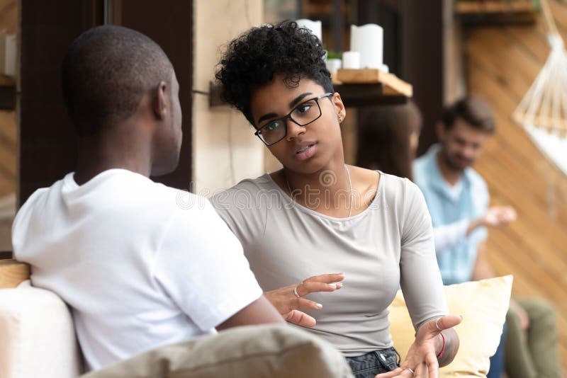 Mujer afroamericana seria que habla con el hombre en café