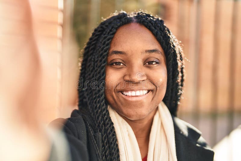 Mujer afroamericana sonriendo confiada haciéndose selfie a cámara en la calle fotografía de archivo libre de regalías