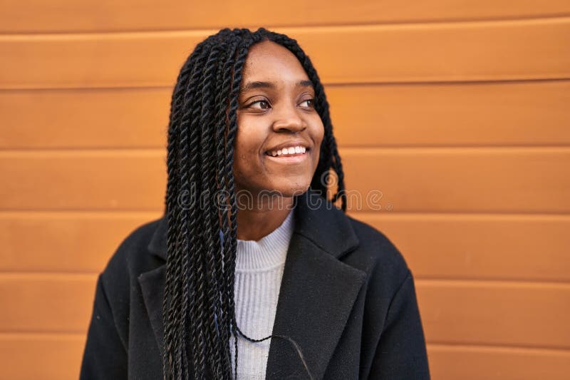 Mujer afroamericana sonriendo confiada mirando al costado sobre fondo aislado de madera imágenes de archivo libres de regalías