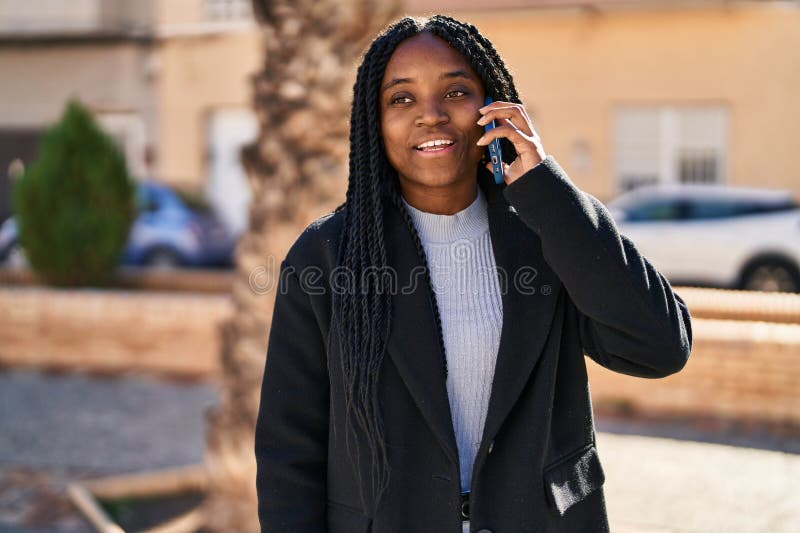 Mujer afroamericana sonriendo segura de sí misma hablando en el smartphone de park imagen de archivo libre de regalías