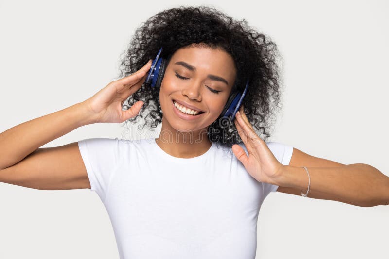 Mujer afroamericana sonriente en audífonos disfrutando de la música favorita