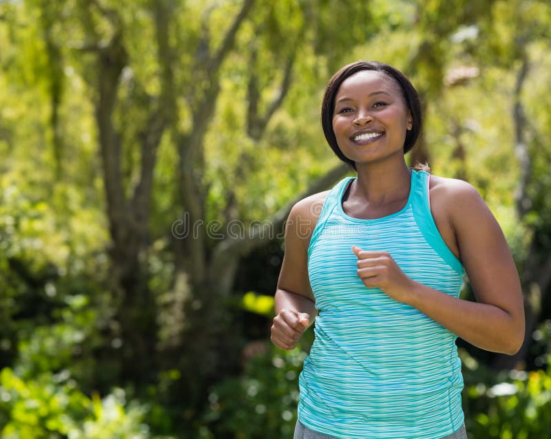 Mujer afroamericana trotando en un parque soleado con tanque color turquesa y espacio para copiar las leggantas grises. Actividad al aire libre ejercicio en movimiento natural vibrante