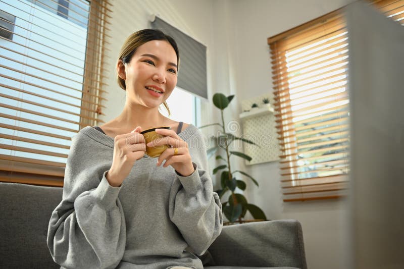 Mujer agradable tomando café y usando laptop en casa navegando por internet viendo películas y comprando en línea fotos de archivo libres de regalías