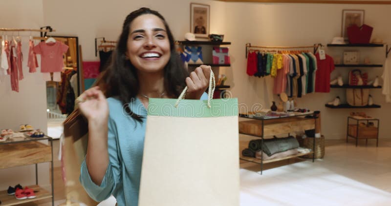 Mujer alegre con bolsas de compras en la tienda de ropa para niños metrajes