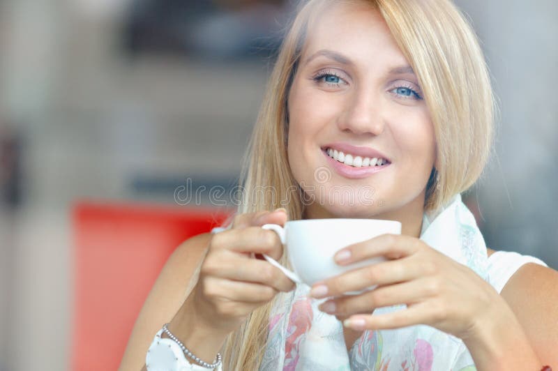 Mujer alegre con la taza de café que se sienta en café y que mira la ventana fotos de archivo Mujer alegre con la taza de café que se sienta en café y que mira la ventana fotos de archivo