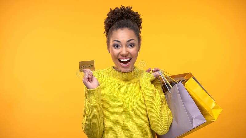 Mujer alegre con los bolsos de compras y la tarjeta de cr? dito de oro, servicio de atenci? n al cliente rico fotografía de archivo libre de regalías