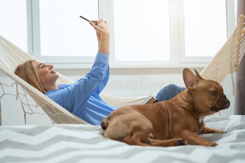 Mujer alegre fotografiándose a sí misma con un smartphone mientras descansaba su mascota imagenes de archivo