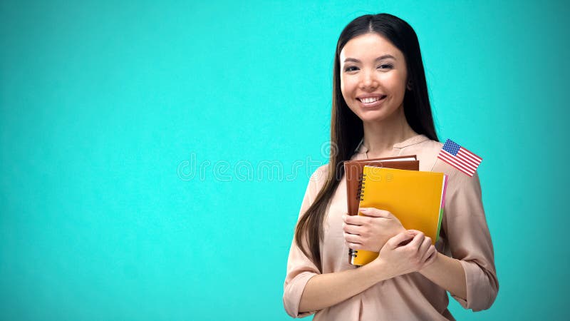 Mujer alegre sosteniendo el libro de la bandera de Estados Unidos, educaciÃ³n en el extranjero, idioma de aprendizaje foto de archivo