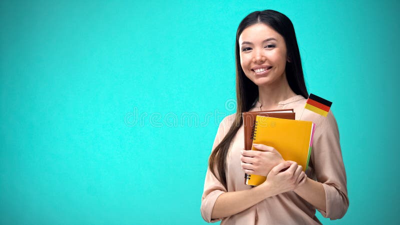 Mujer alegre sostiene libro de bandera alemÃ¡n, educaciÃ³n en el extranjero, idioma de aprendizaje fotos de archivo