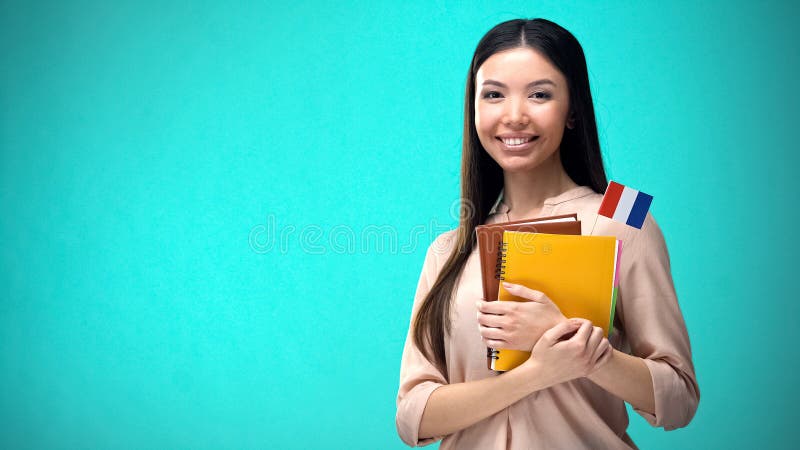 Mujer alegre sostiene libro de bandera francesa, educaciÃ³n en el extranjero, idioma de aprendizaje foto de archivo