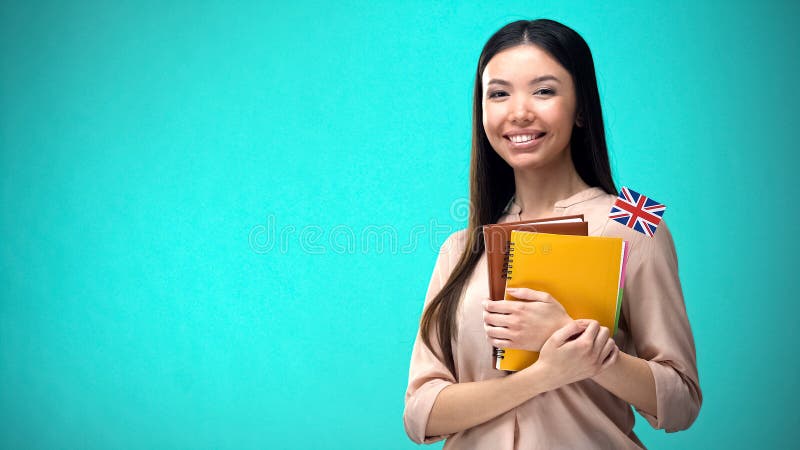 Mujer alegre sostiene libro de la bandera britÃ¡nica, educaciÃ³n en el extranjero, idioma de aprendizaje imagen de archivo