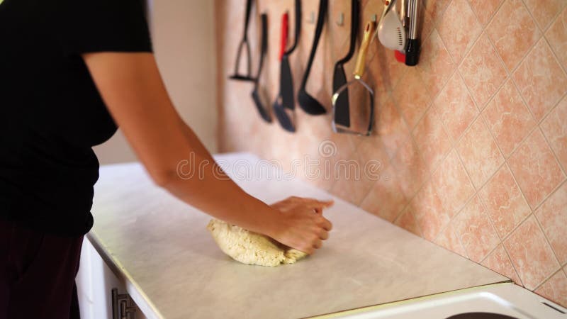 Mujer amasando masa fresca blanca con las manos sobre la mesa en la cocina almacen de video